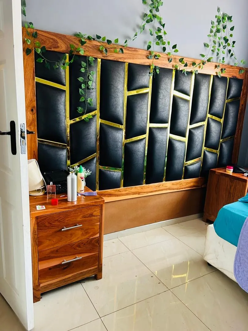 Wood-framed bedhead with black padded panels and gold trim